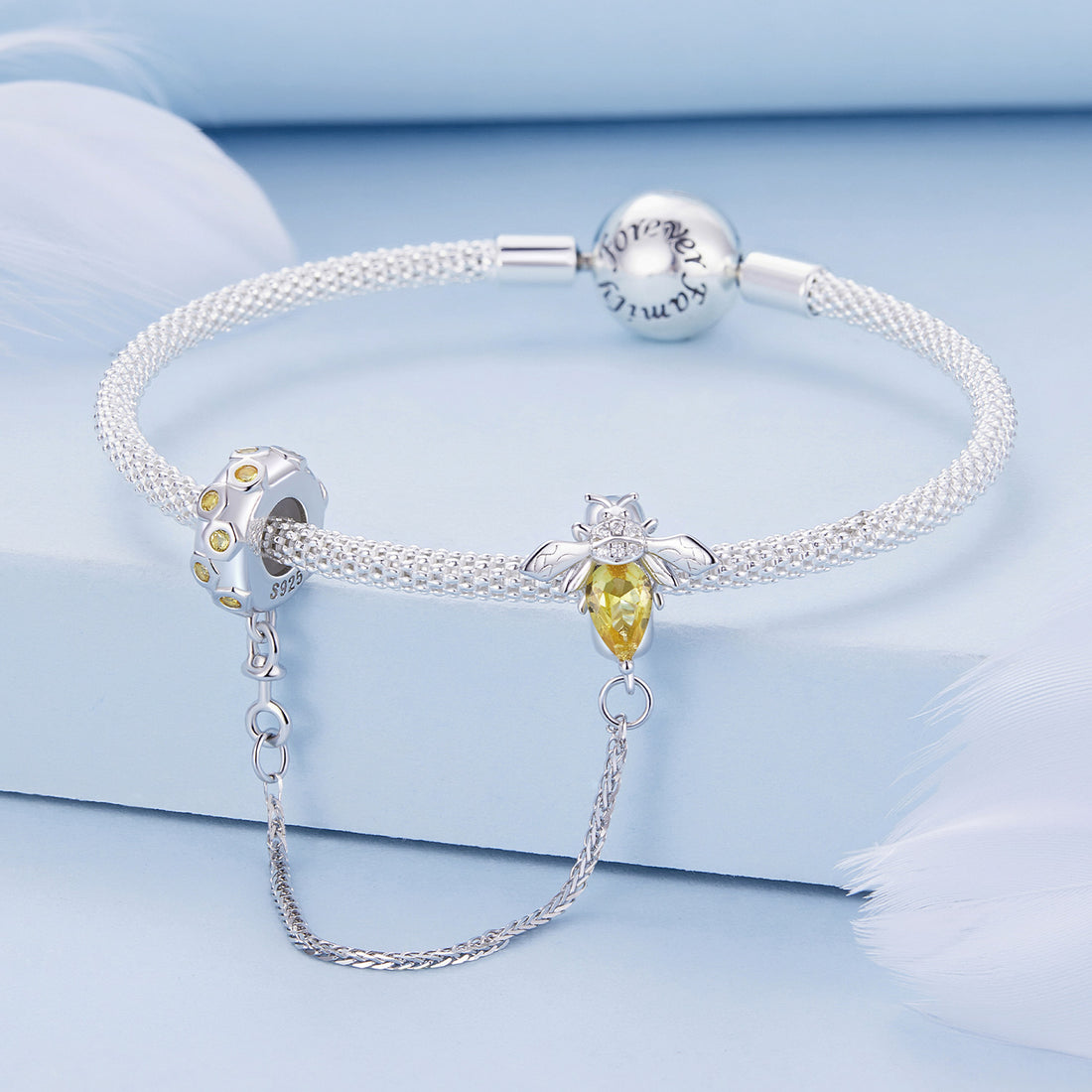 Silver bee-shaped charm with yellow gemstone on a white background