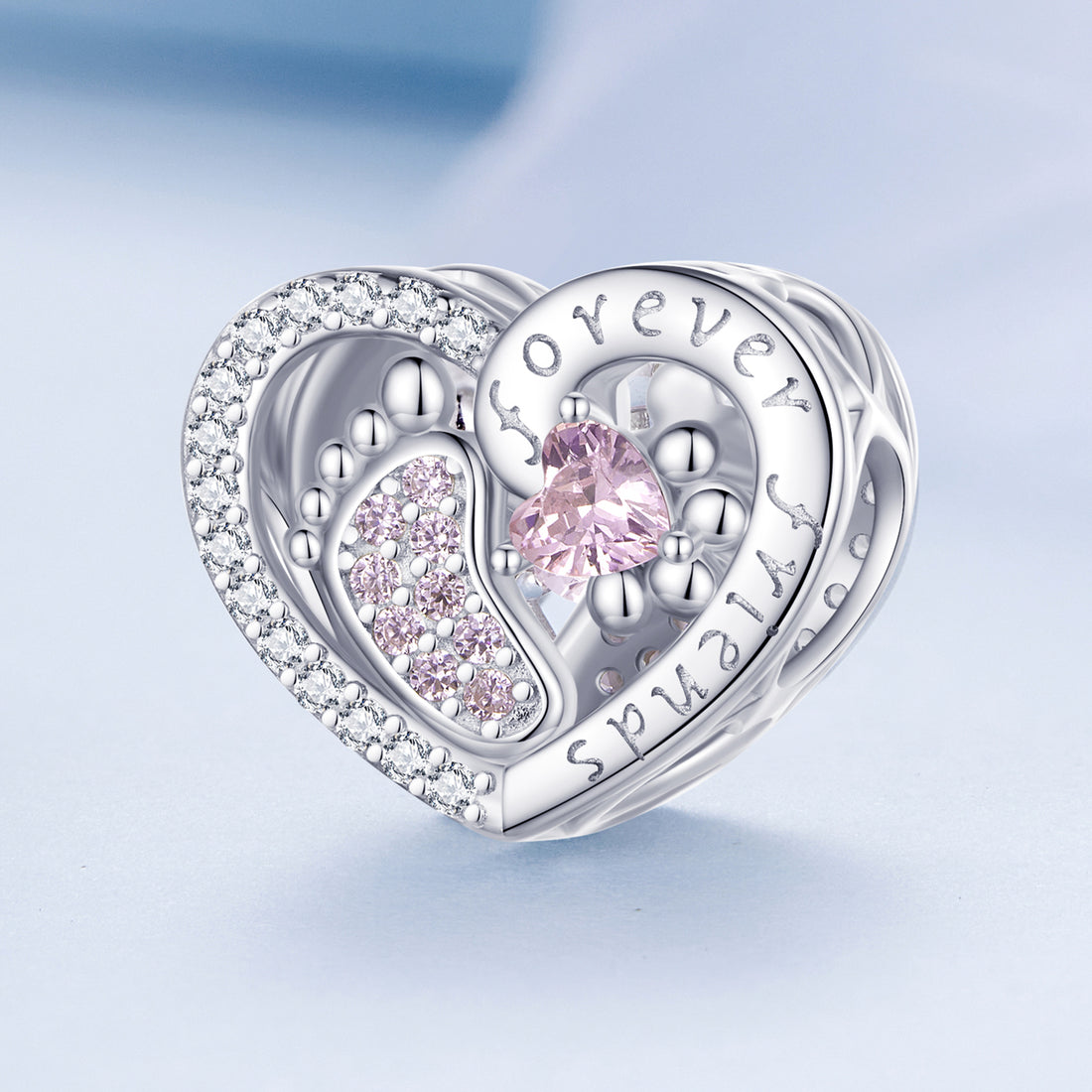 Heart-shaped silver charm with pink gemstones on a light blue background