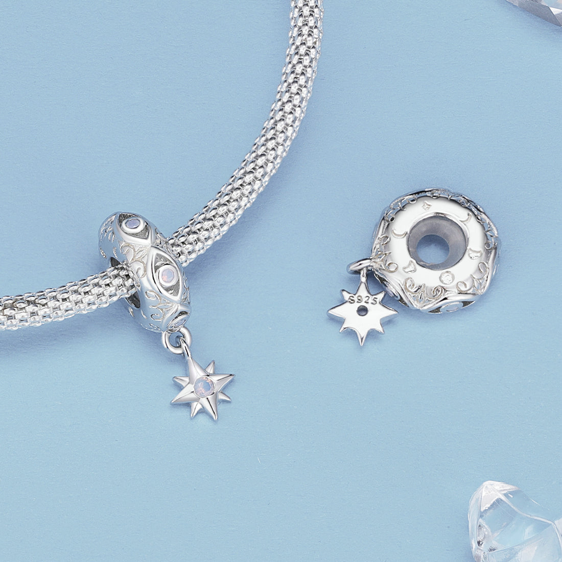 Silver charm with star design and moonstone on a white background