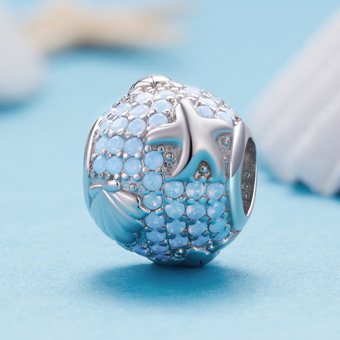 Silver charm with blue gemstones on a light blue background