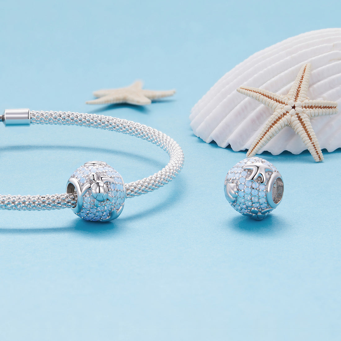 Silver charm with blue gemstones on a light blue background