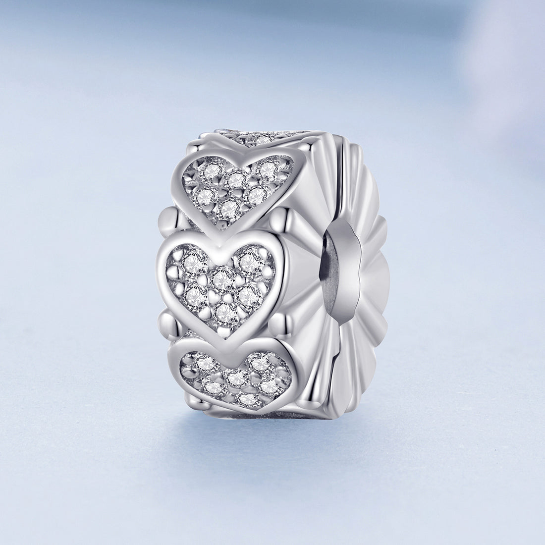 Silver charm with heart designs on a light blue background