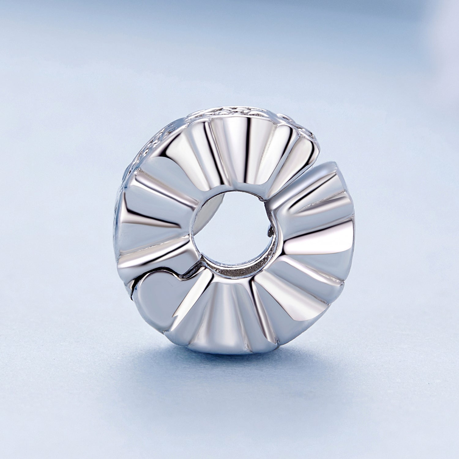 Silver ring with a textured design on a light blue background