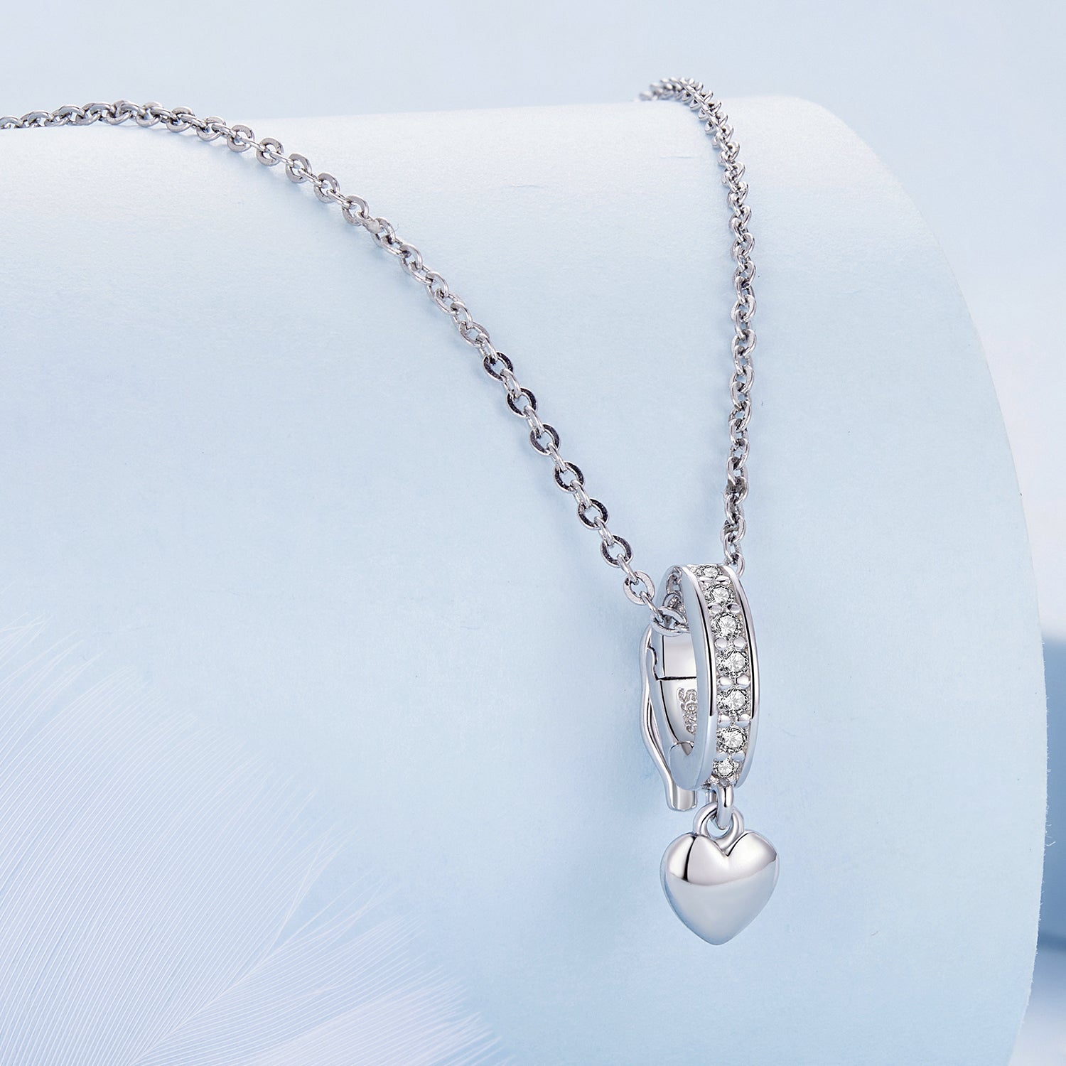 Silver heart-shaped pendant necklace on a light blue background