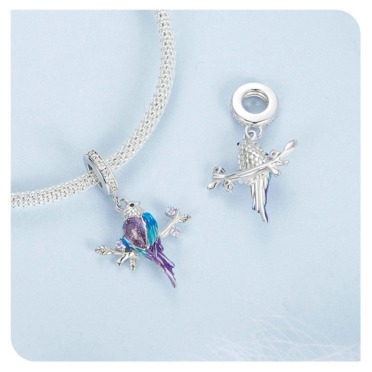 Silver bird charm with purple and blue colors on a white background