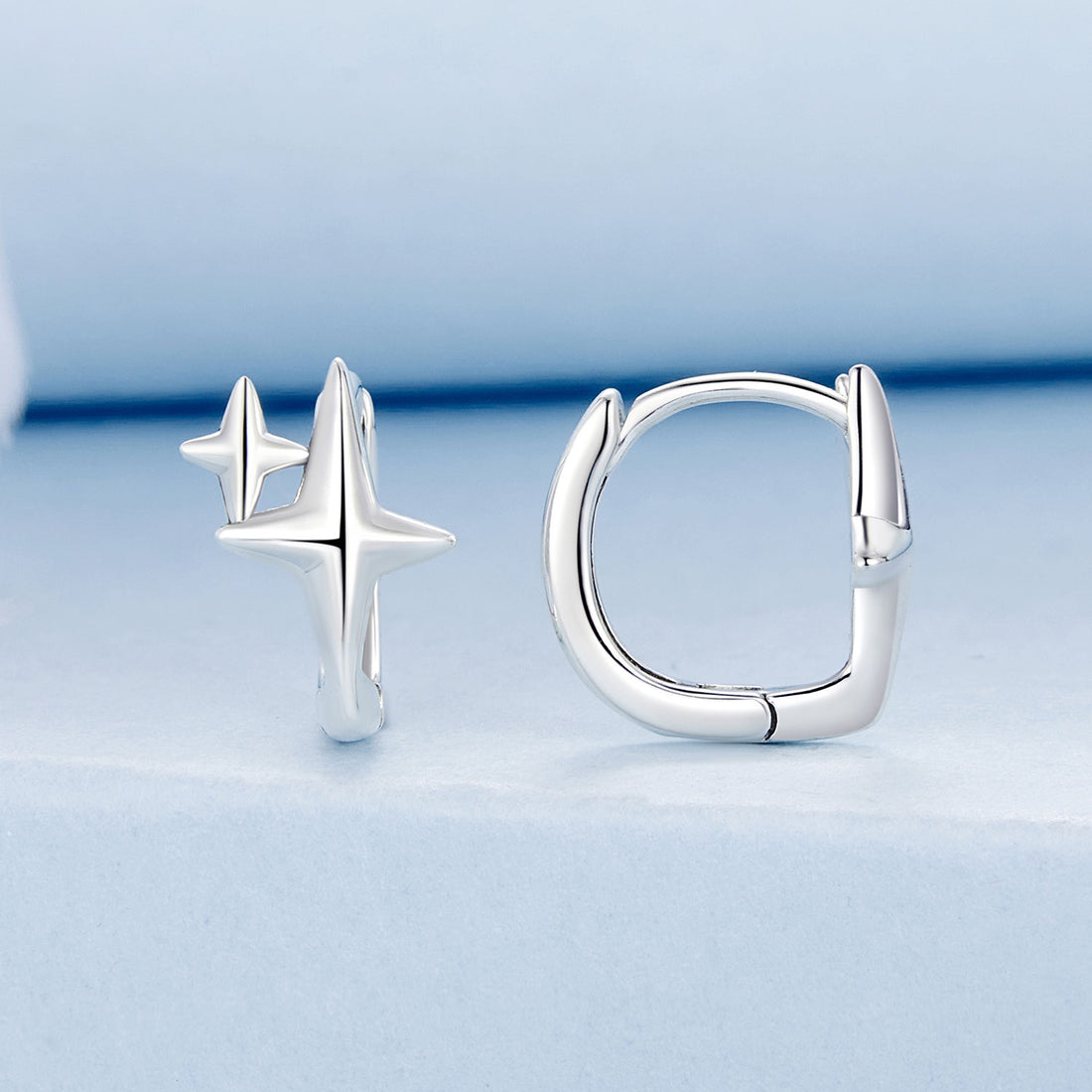 Silver star-shaped earrings on a white background