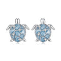 Turtle-shaped earrings with blue enamel and clear stones on a white background