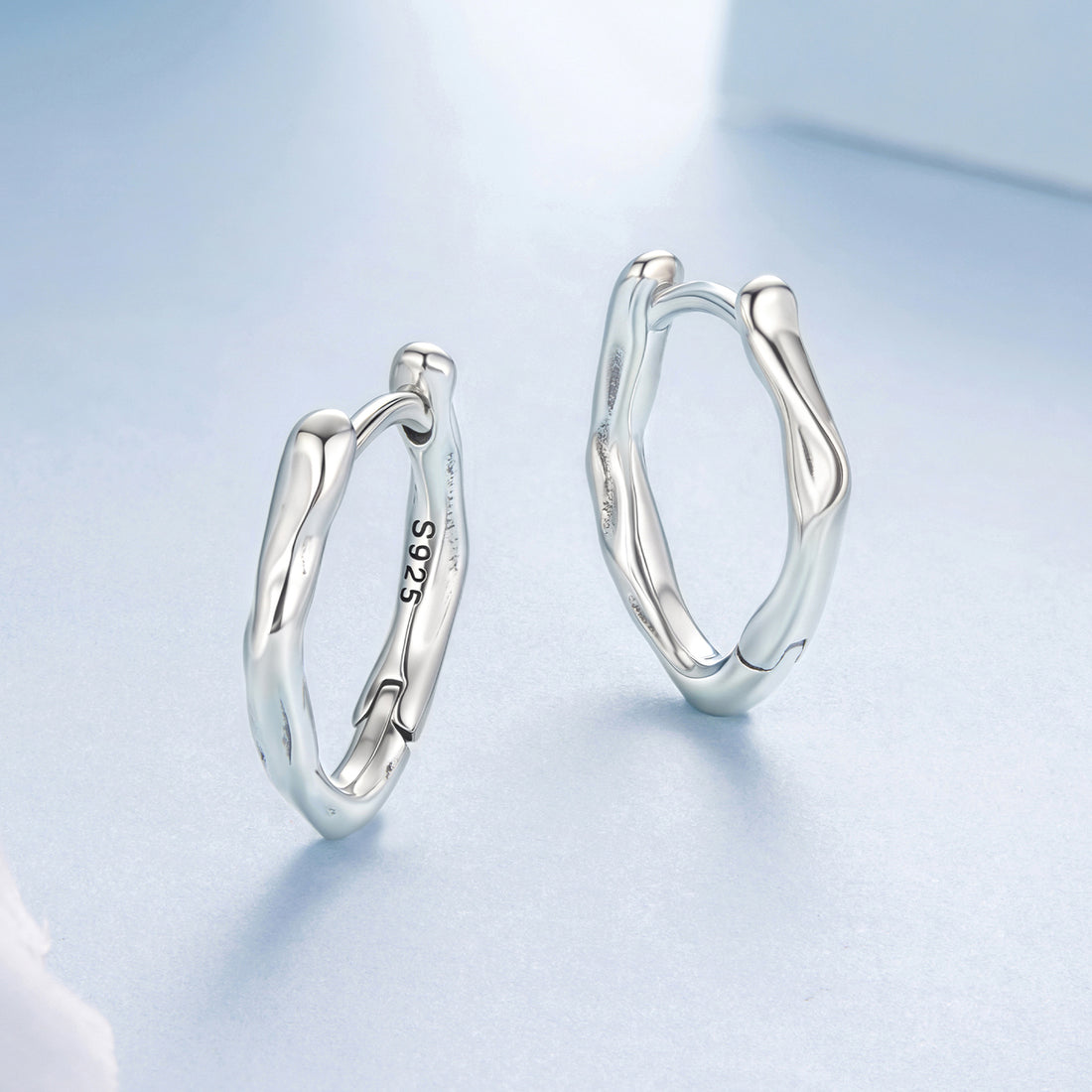 Silver hoop earrings on a light blue background