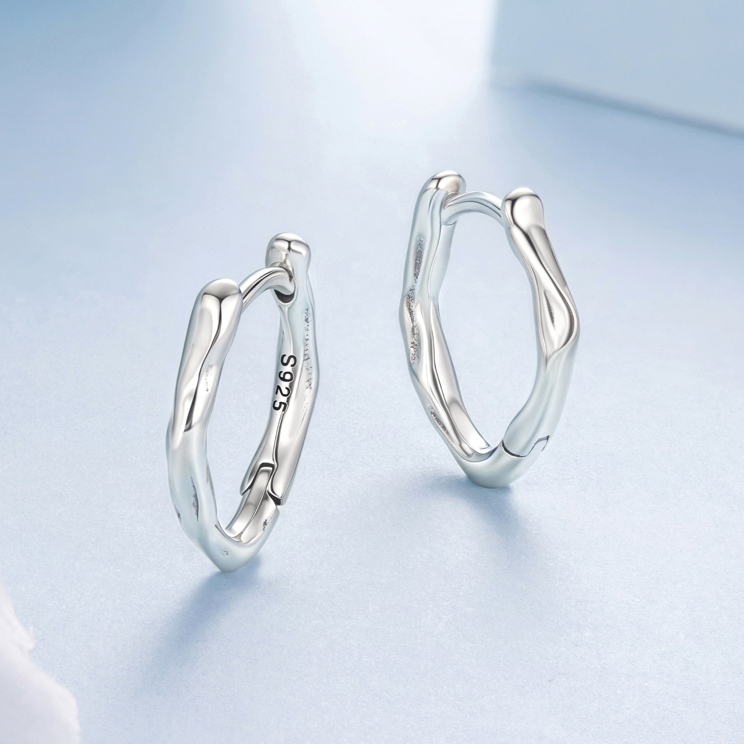 Silver hoop earrings on a light blue background