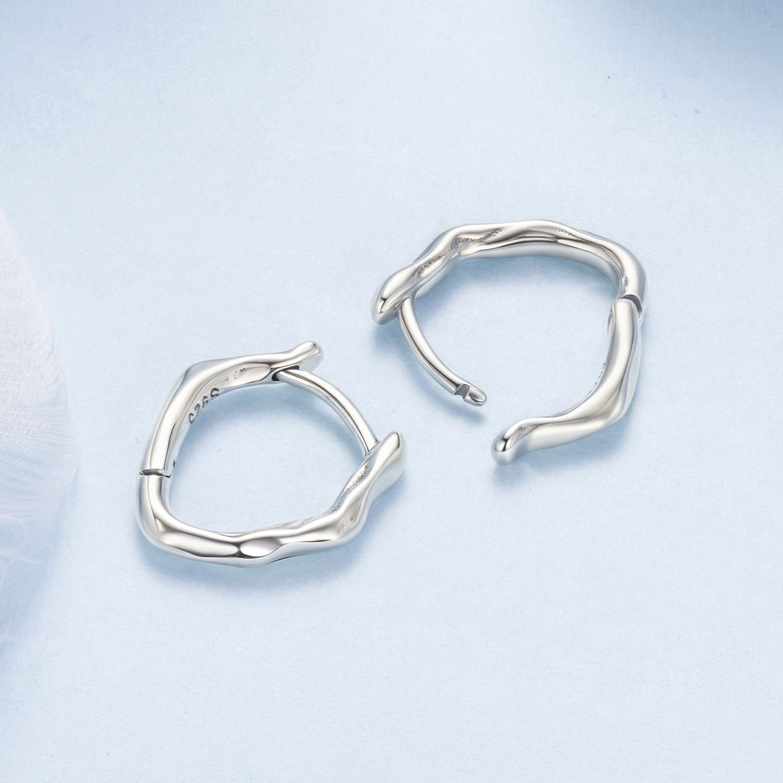 Silver hoop earrings on a light blue background