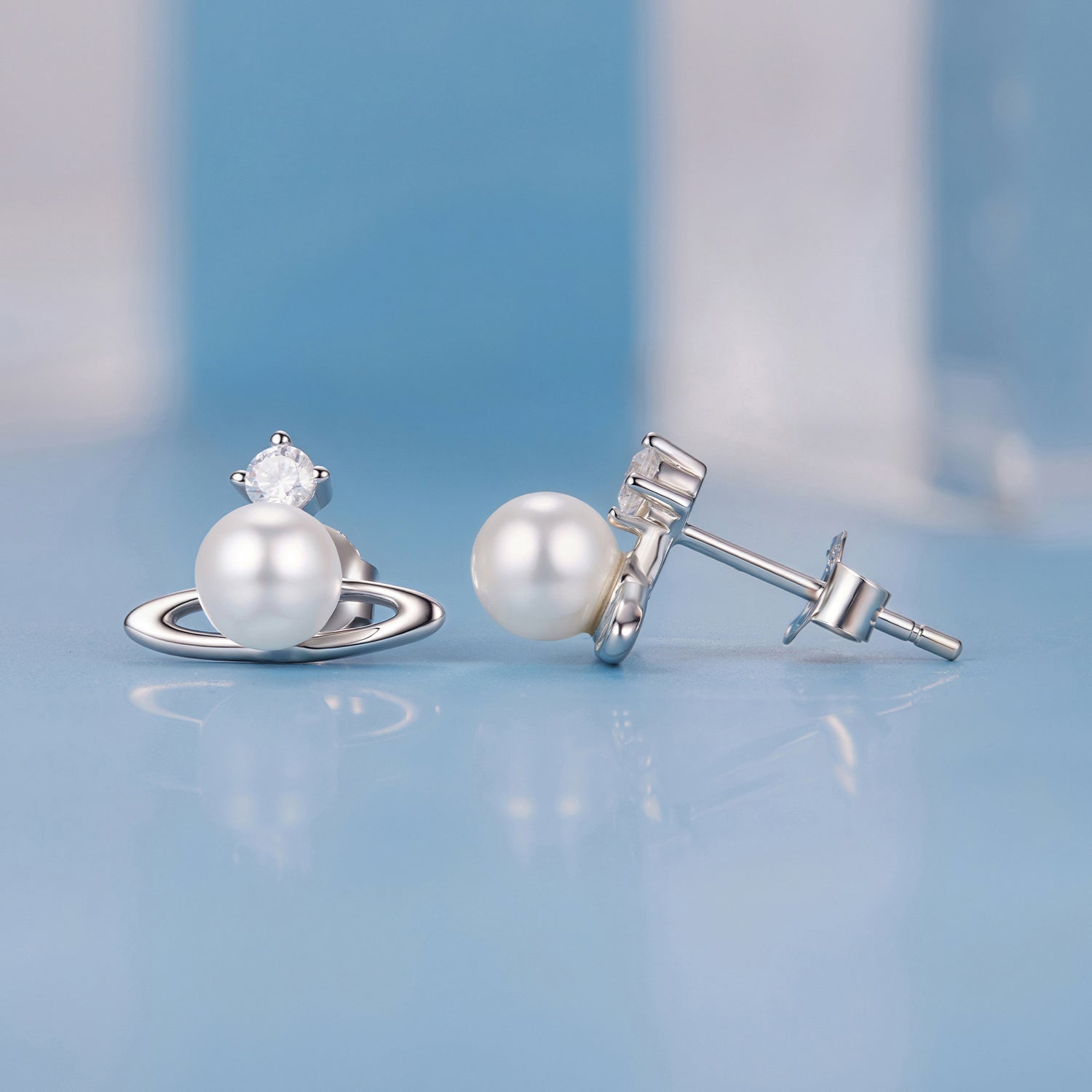 Pearl earrings with silver settings on a light blue background