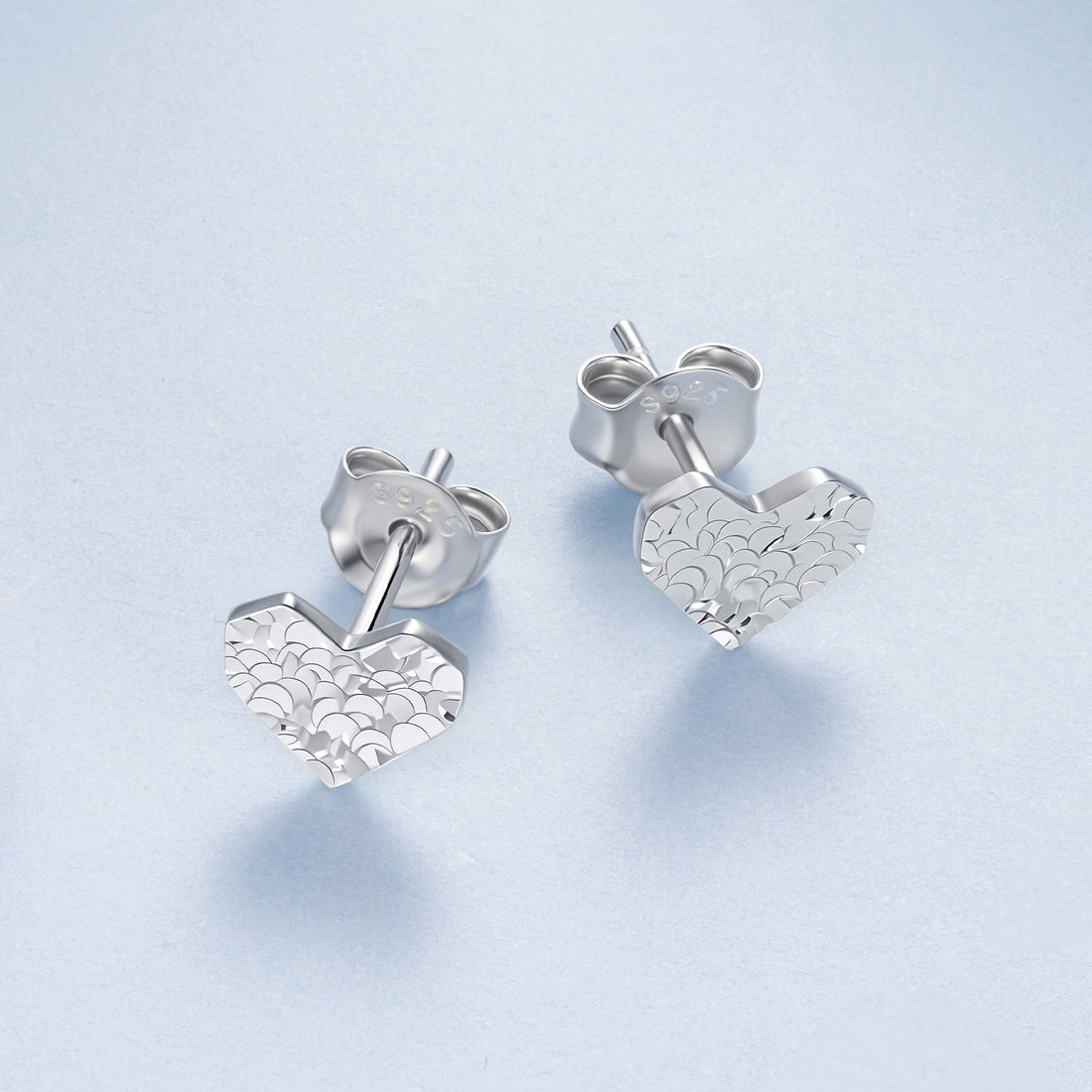 Silver heart-shaped earrings on a light blue background
