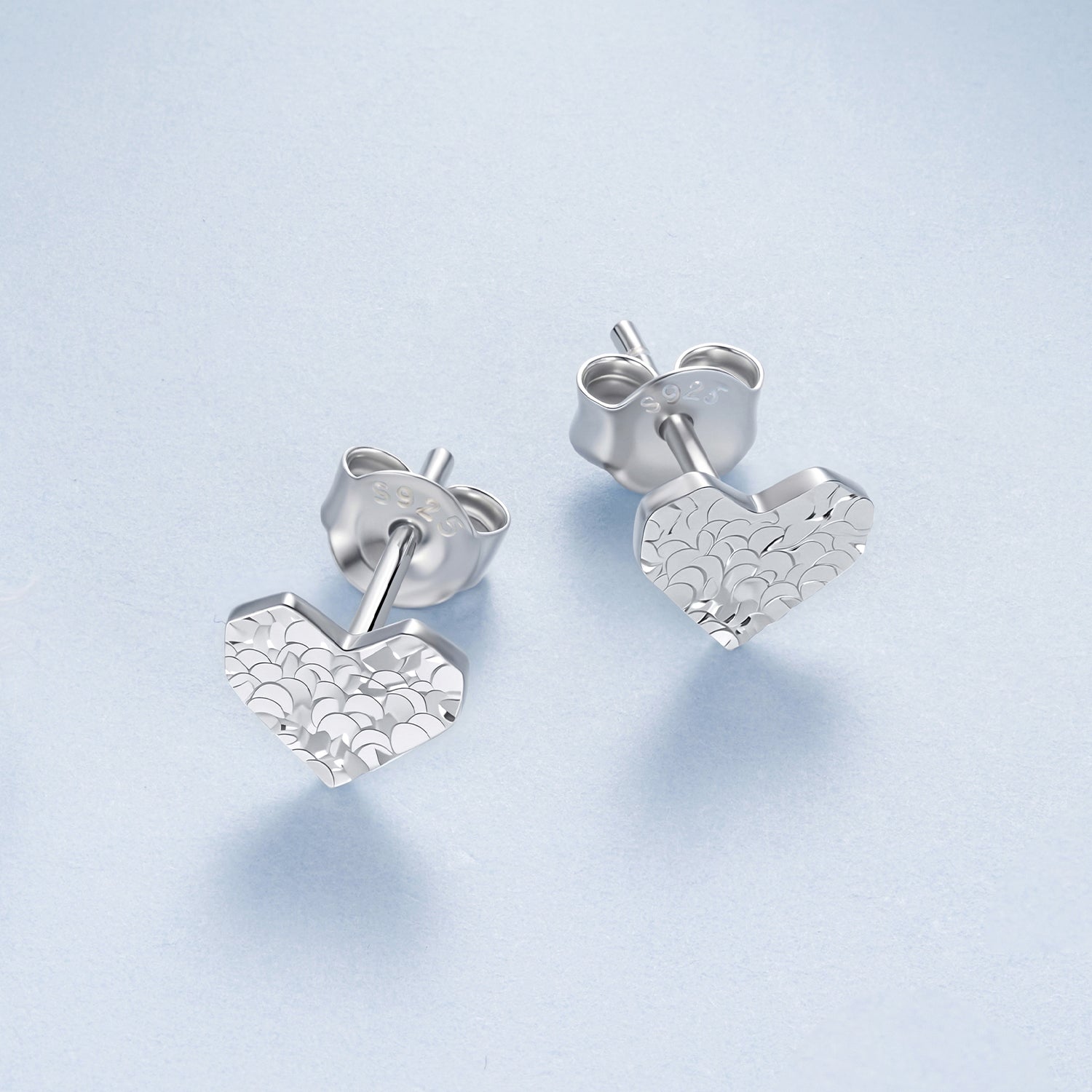 Silver heart-shaped earrings on a light blue background