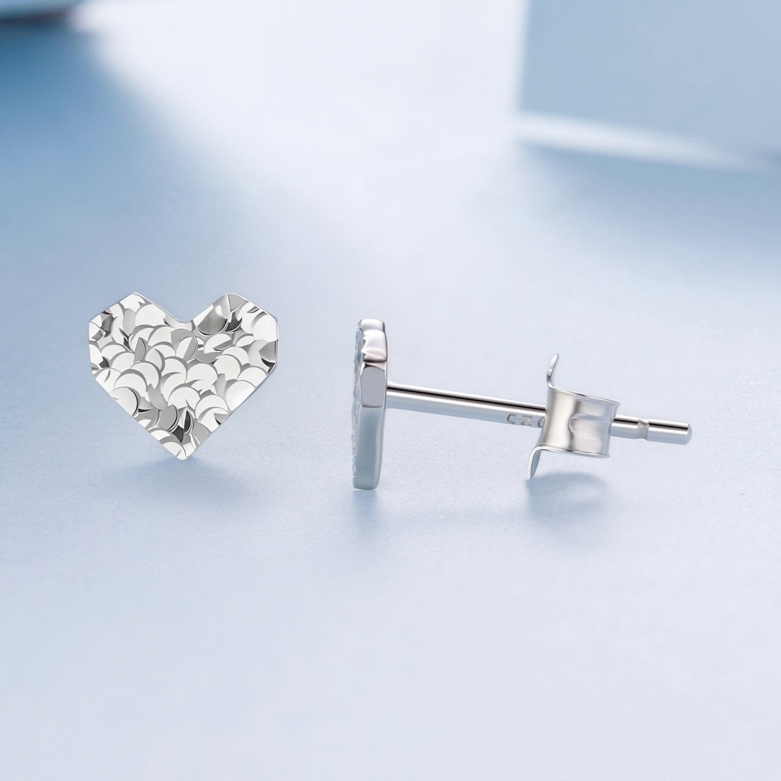 Silver heart-shaped earrings on a light blue background