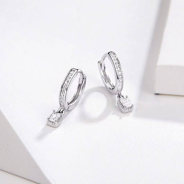 Silver hoop earrings with square drop charms on a white background