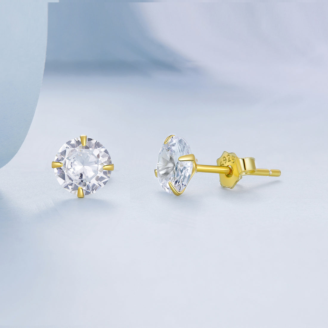 Gold stud earrings with clear gemstones on a white background