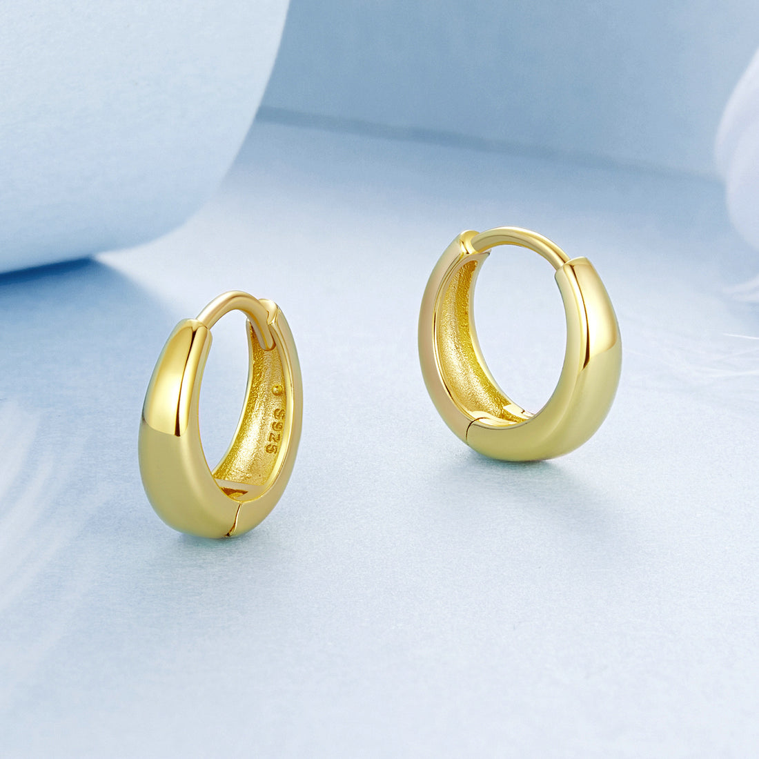 Gold hoop earrings on a light blue background