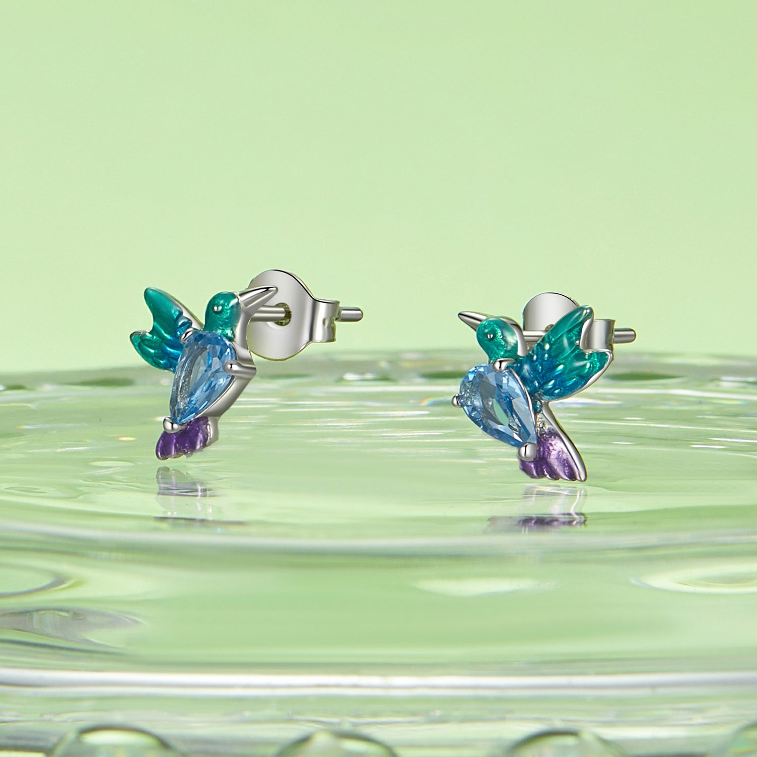 Colorful hummingbird-shaped earrings on a green background