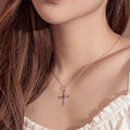 Close-up of a woman wearing a necklace with a cross pendant on a neutral background