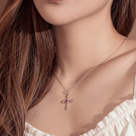 Close-up of a woman wearing a necklace with a cross pendant on a neutral background