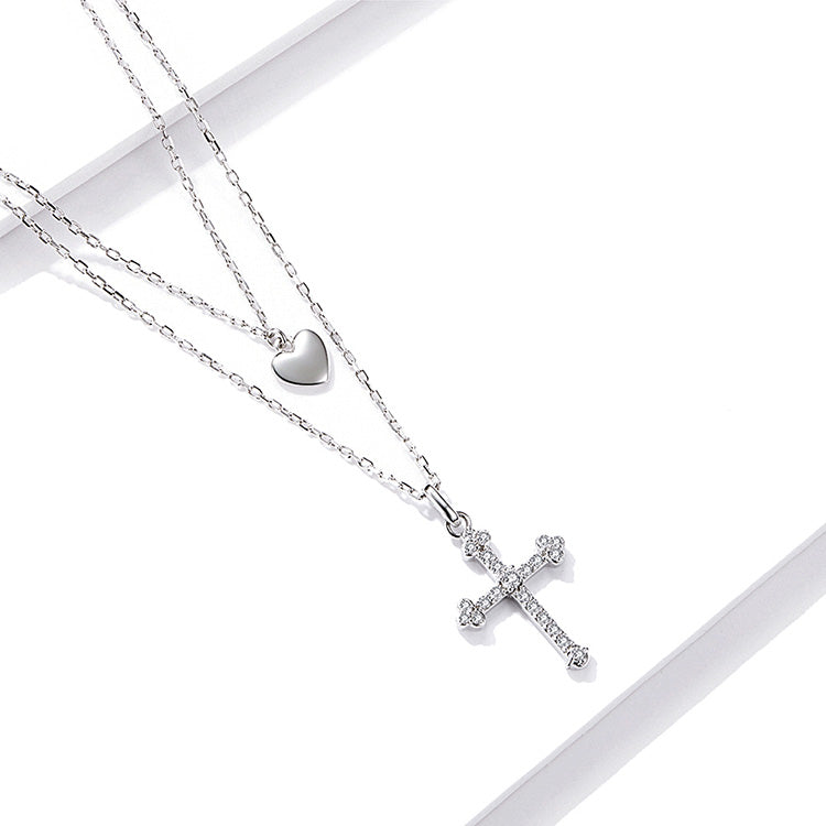 Silver necklace with heart and cross pendants on a white background