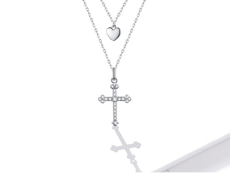 Silver necklace with heart and cross pendants on a white background