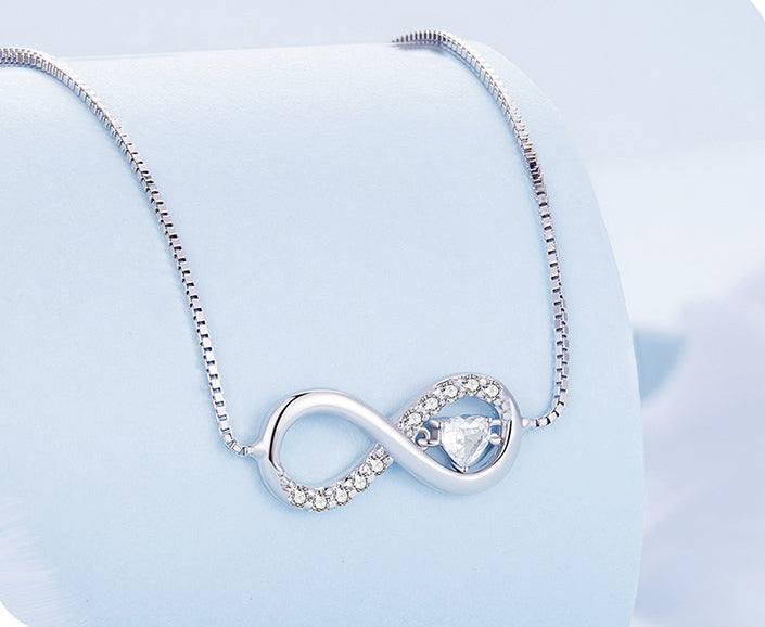 Silver infinity necklace with a heart pendant on a light blue background