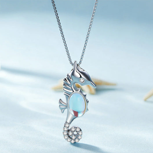 Seahorse-shaped necklace with a blue gemstone on a light blue background