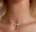 Silver necklace worn by a person with a neutral background