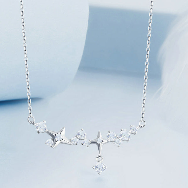 Silver necklace with star-shaped pendants on a light blue background