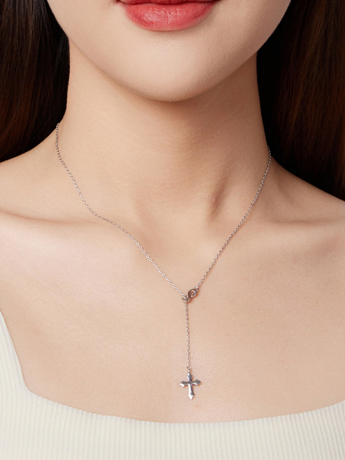 Necklace with a cross pendant worn by a person, with a neutral background