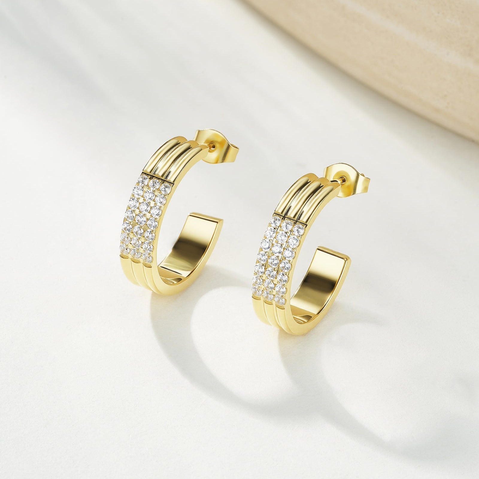 Gold hoop earrings with embedded stones on a light background
