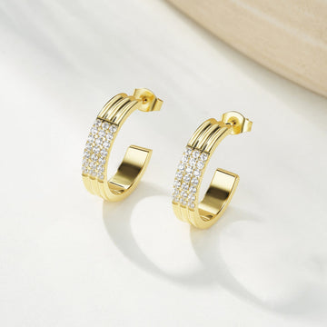 Gold hoop earrings with embedded stones on a light background