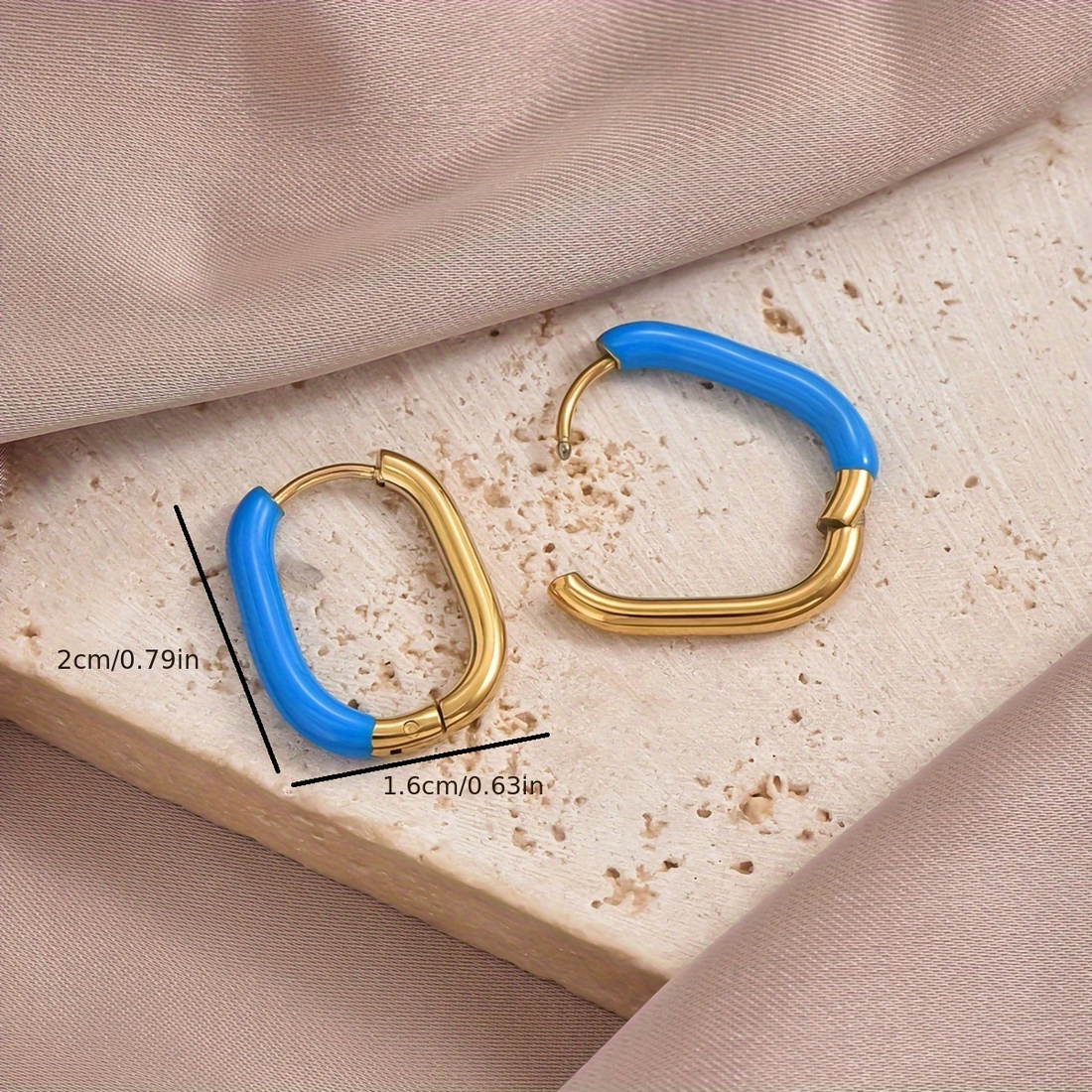 Gold hoop earrings with blue ceramic ends on a white surface