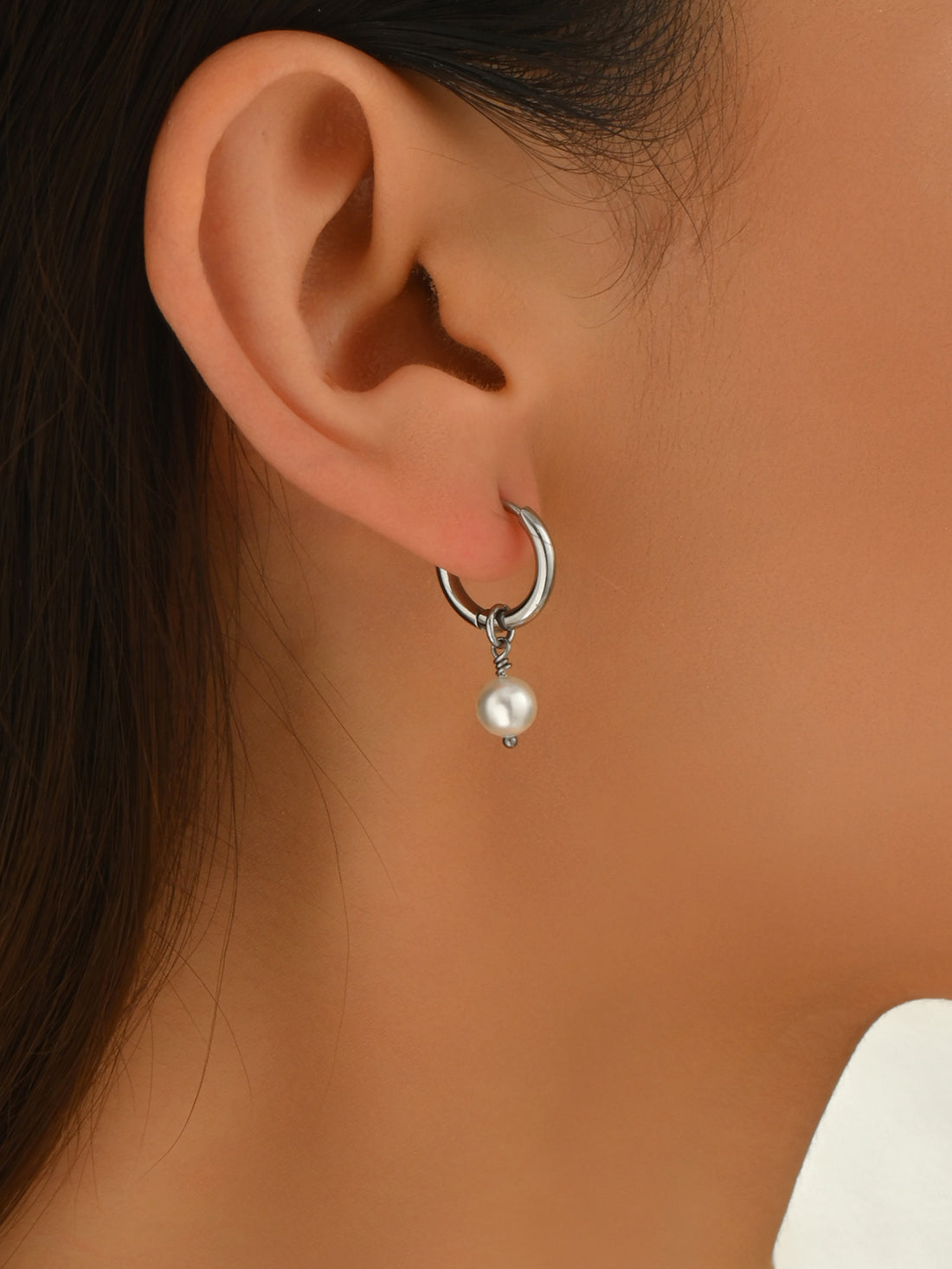 Silver hoop earrings with pearls on a light background