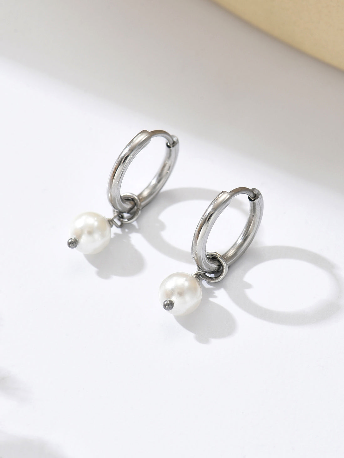 Silver hoop earrings with pearls on a light background