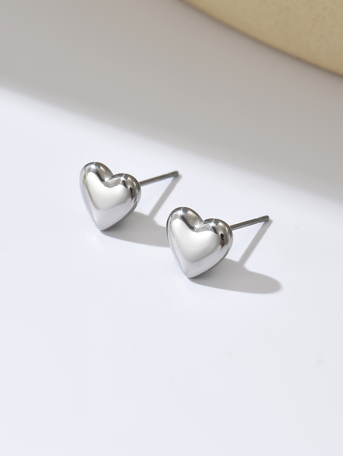 Heart-shaped silver earrings on a light background