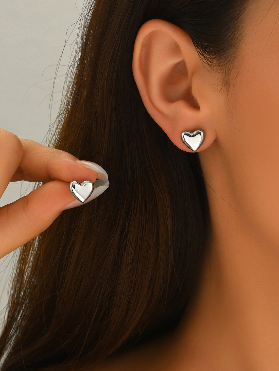 Heart-shaped silver earrings on a light background