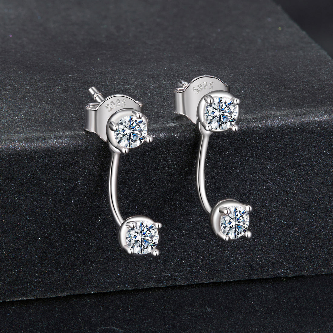 Silver earrings with clear gemstones on a black background