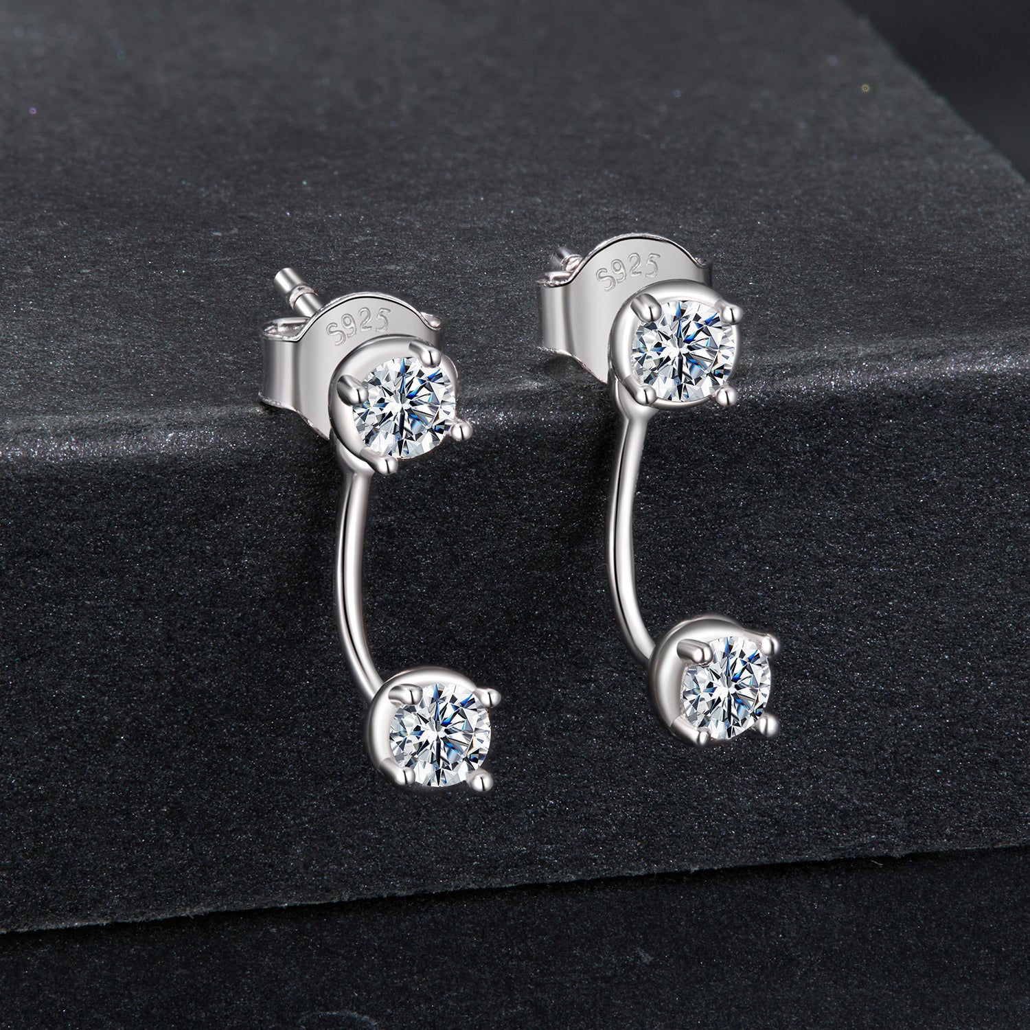 Silver earrings with clear gemstones on a black background