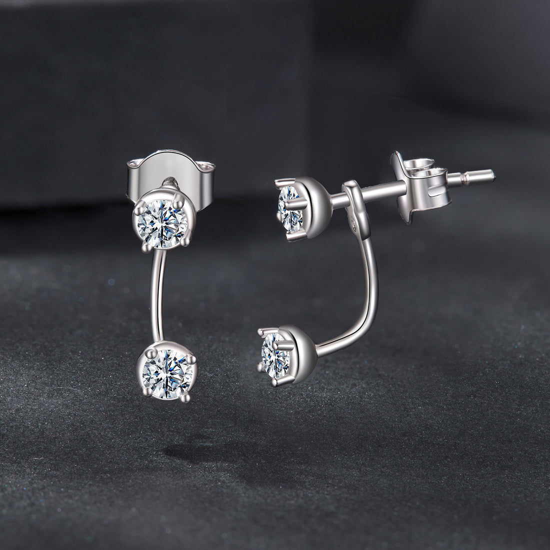 Silver earrings with clear gemstones on a black background