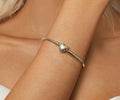Silver bracelet with a heart charm on a wrist, brand 'YIZIV' visible