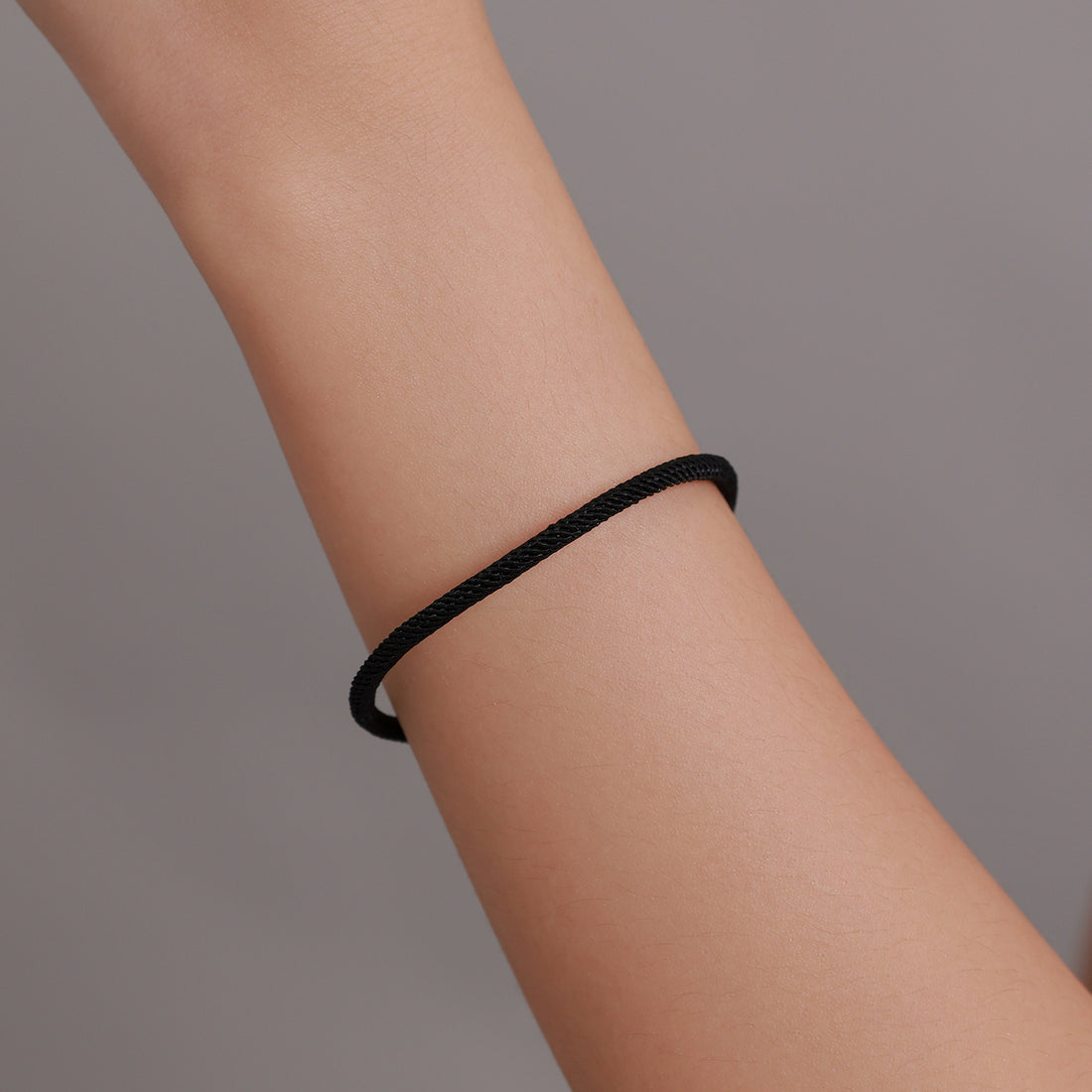 Black braided bracelet with silver clasp on a white background