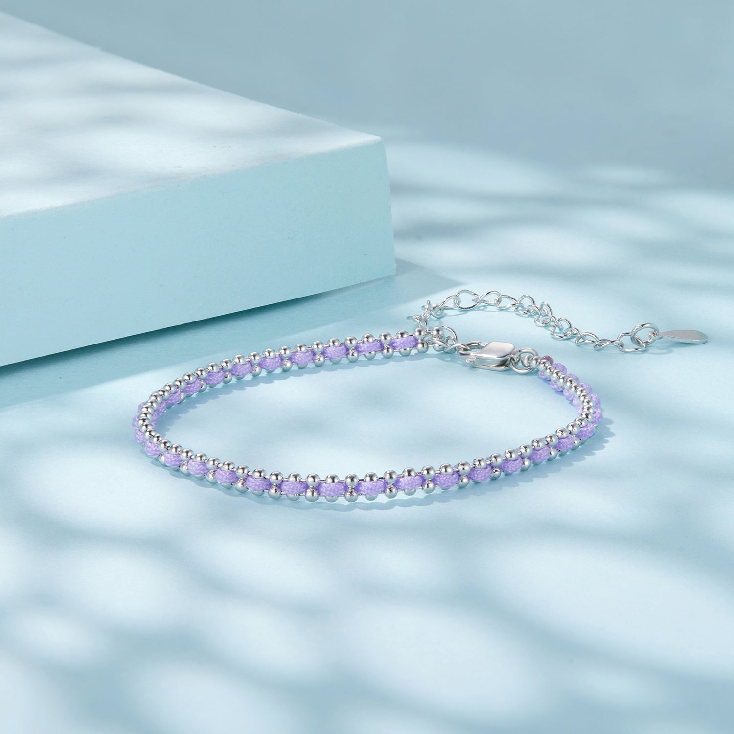 Silver bracelet with purple beads on a light blue background