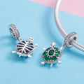 Two turtle-shaped charms on a blue and pink background