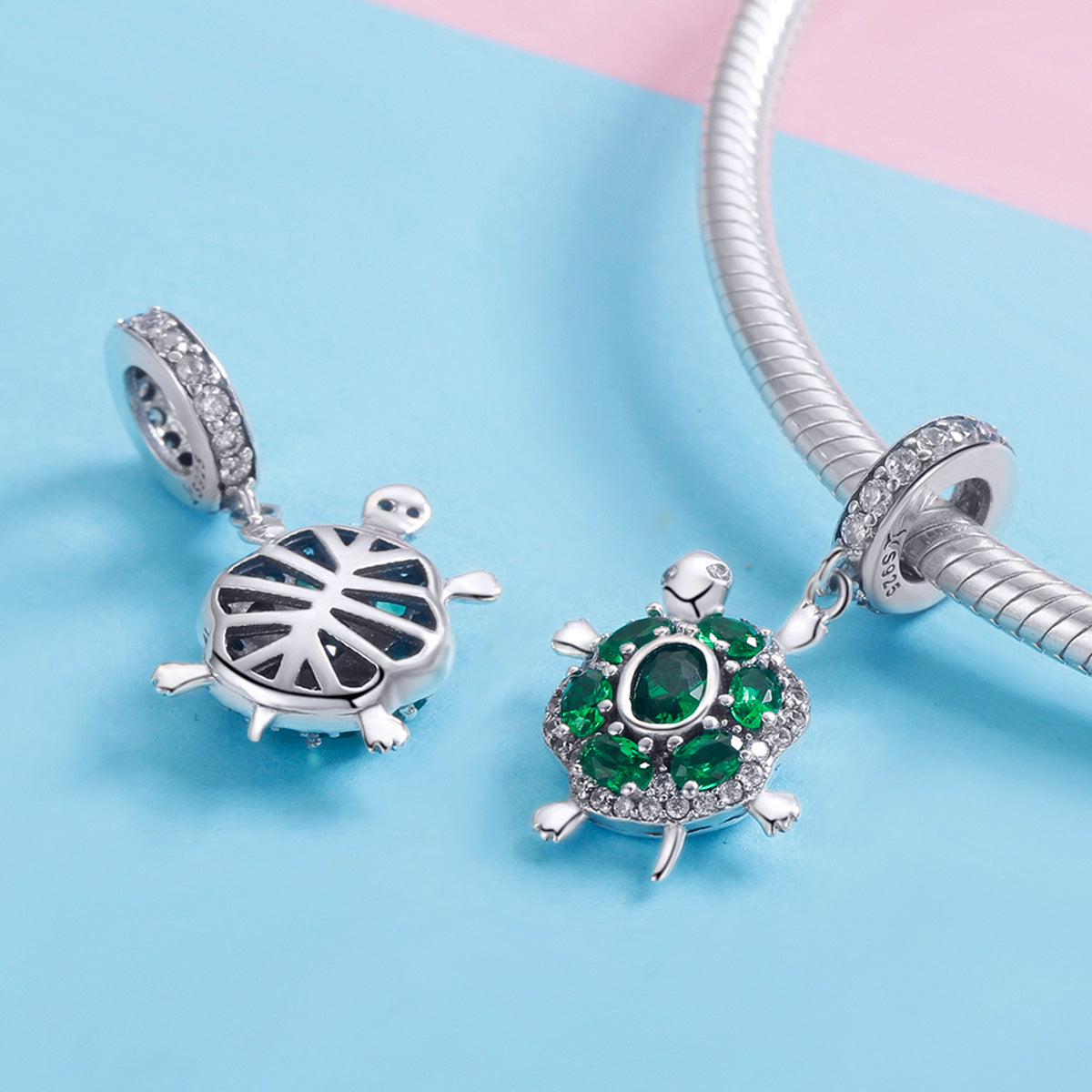 Two turtle-shaped charms on a blue and pink background