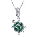 Tortoise-shaped pendant with green gemstones on a white background