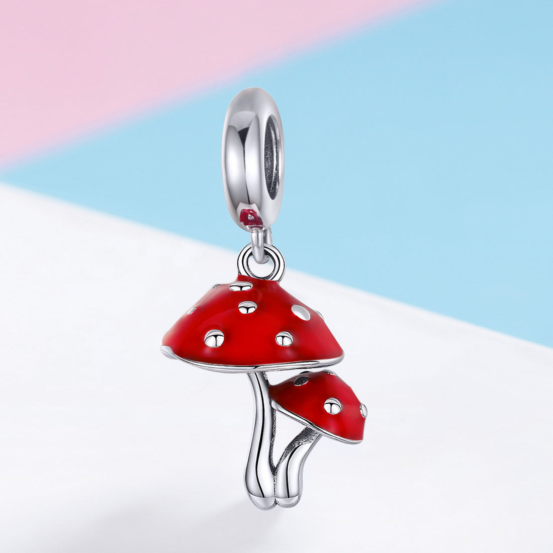 Red mushroom-shaped pendant with silver accents on a light blue and white background