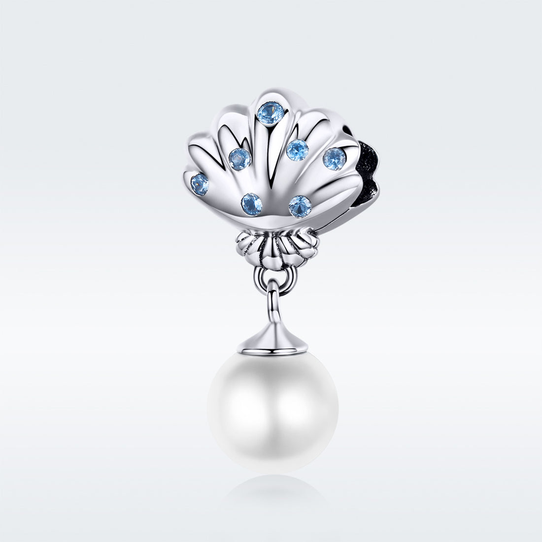 Pearl charm with shell design and blue stones on a colorful background