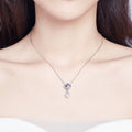 Necklace with a pendant featuring a heart and pearl on a plain background